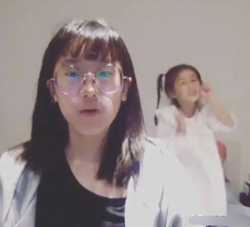 贾静雯大女儿做功课,咘咘在身后手舞足蹈扮鬼脸,淘气又可爱